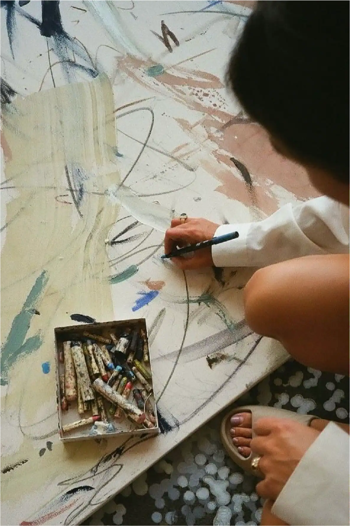 Bambino che crea arte astratta con gessetti colorati su una grande tela.
