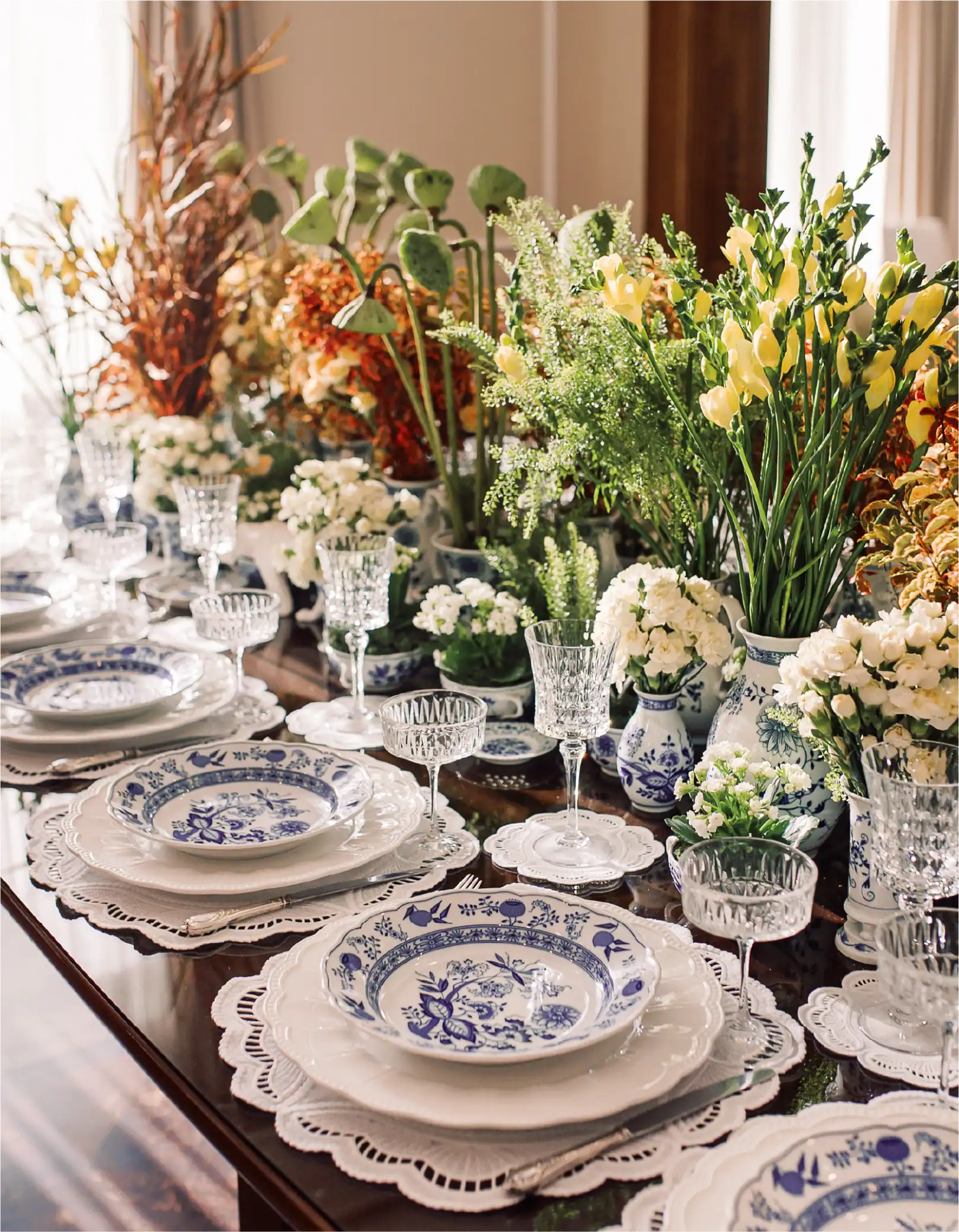 Bella composizione floreale da tavola con porcellane, bicchieri e fiori freschi.