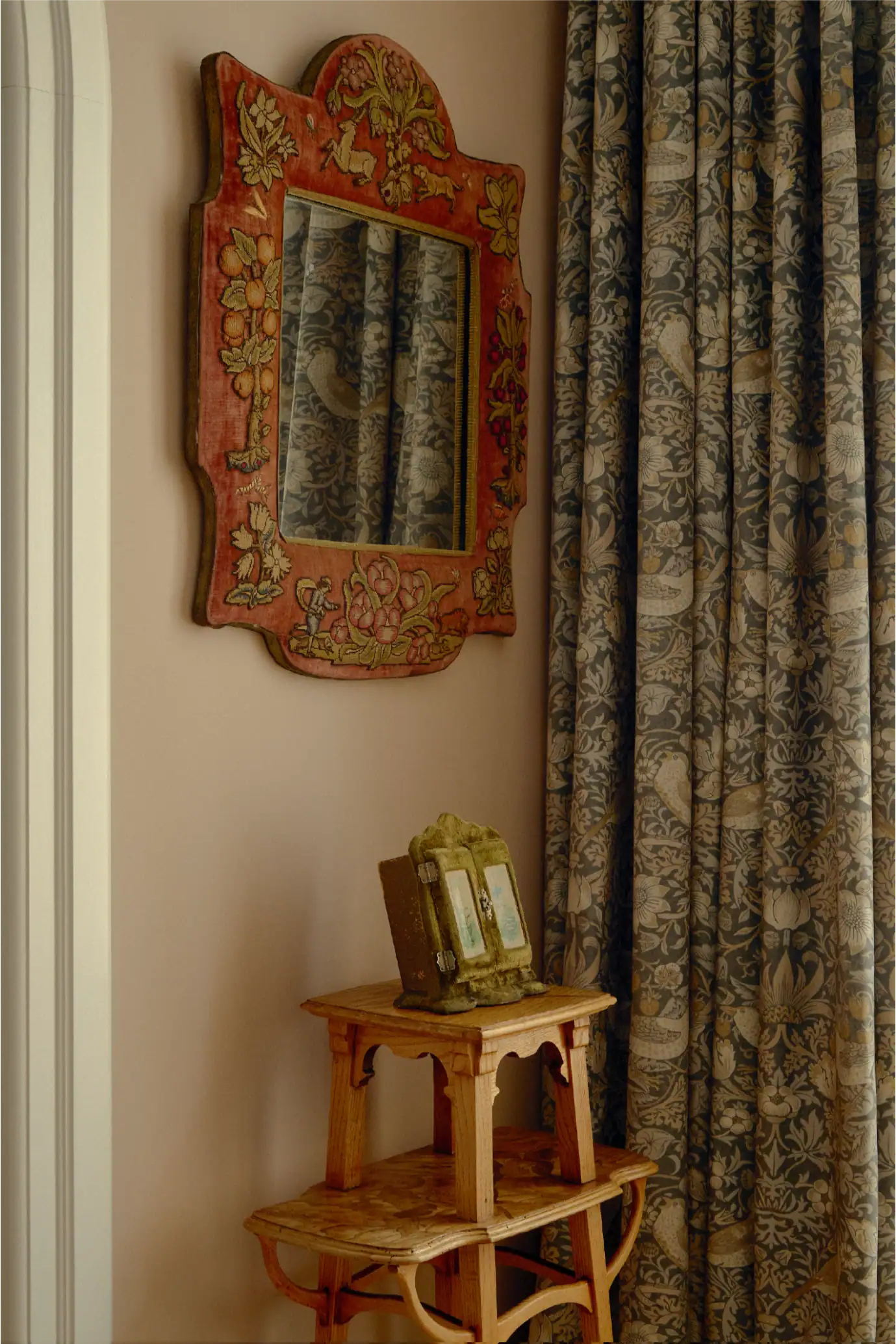 Specchio floreale decorativo con cornice intagliata accanto a eleganti drappeggi.
